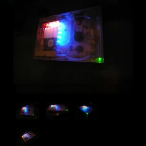 May include: A clear plastic case containing a circuit board. The case is illuminated by red, blue and green LEDs.