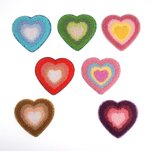 May include: Seven felt heart-shaped patches in various colors, including red, pink, blue, green, brown, and purple. Each heart has a smaller white heart in the center.