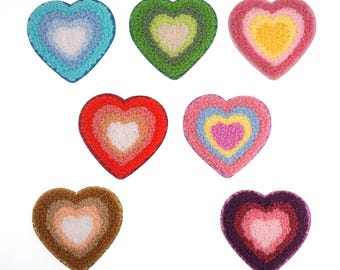May include: Seven felt heart-shaped patches in various colors, including red, pink, blue, green, brown, and purple. Each heart has a smaller white heart in the center.