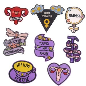 Peut inclure: Dix patchs brodés thermocollants avec des slogans féministes et stimulants. Les patchs sont de couleur violette, rose, blanche et noire avec différents motifs, notamment un utérus, une libellule, un marteau et un cœur.