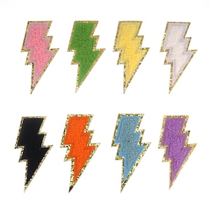 Op de afbeelding: Set van tien kleurrijke bliksemvormige patches met een gouden glitterrand. De patches zijn gemaakt van pluche stof en perfect om kleding, tassen of andere accessoires een vleugje kleur te geven.
