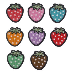 May include: Set of nine embroidered iron-on patches featuring strawberries in various colors with white polka dots. The strawberries are outlined in black.