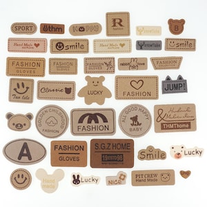 May include: A collection of brown paper craft stickers with various designs and text. The stickers feature words like "Fashion", "Lucky", "Smile", "Hand Made", and "Jump!" along with various animal and heart designs.
