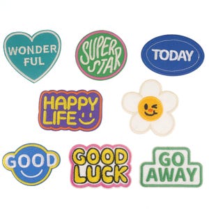 May include: Nine colourful iron-on patches with various phrases and designs. The patches include "WonderFul", "Super Star", "Today", "Happy Life", "Good", "Good Luck", "Go Away", a daisy with a smiley face, and a heart.