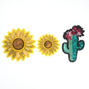 May include: Three embroidered iron-on patches: a yellow sunflower, a smaller yellow sunflower, and a green cactus with pink flowers.