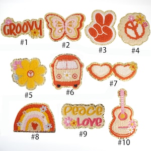 Könnte beinhalten: Zehn bunte Bügelbilder mit einem groovy Thema. Die Patches zeigen ein Peace-Zeichen, einen Schmetterling, einen Regenbogen, einen groovy Text, eine Blume, einen Van, eine herzförmige Sonnenbrille, eine Gitarre und einen Peace-and-Love-Text.