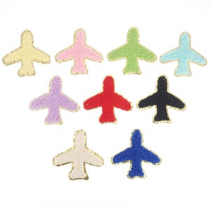 May include: Ten felt airplane patches in various colours, including red, blue, green, yellow, white, black, and purple. Each patch has a gold outline.