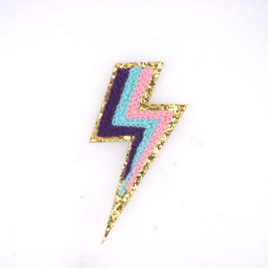 May include: A gold glitter lightning bolt patch with pink, blue, and purple yarn embroidery.