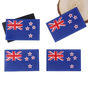 May include: Four blue rectangular patches featuring the New Zealand flag design. Each patch has a Union Jack in the upper left corner and four to five red stars on the right. The patches are made of fabric and have a stitched border.
