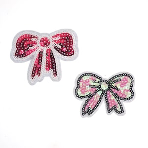 Op de afbeelding: Twee pailletten strik patches. Eén is roze en iriserend, de andere is rood en roze.