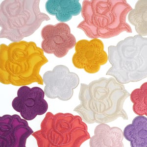 May include: Assortment of colorful embroidered flower patches in various shapes and sizes. The patches include roses and other floral designs in shades of pink, yellow, purple, white, and teal. Perfect for fabric embellishment.