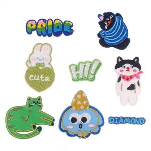 Puede incluir: Un conjunto de nueve parches para planchar con diferentes diseños, que incluyen un arcoíris con la palabra "PRIDE", un corazón con la palabra "cute", un gato con una bandana rosa, un personaje azul con un sombrero amarillo, un gato verde y las palabras "HI!" y "DIAMOND".