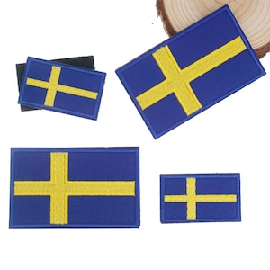 Może przedstawiać: Kolekcja niebiesko-żółtych haftowanych naszywek z flagą Szwecji. Naszywki różnią się rozmiarem i kształtem, z żółtym krzyżem na niebieskim tle. Naszywki są prawdopodobnie przeznaczone na odzież lub akcesoria.