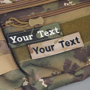 May include: Close-up of two rectangular patches with the text "Your Text" in white and black lettering. The patches are on a camouflage background. The top patch has a black border, while the bottom patch has a tan border.