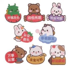 May include: Set of 9 embroidered iron-on patches featuring cute cartoon animals and motivational phrases in Chinese characters. The patches include a green monster, a brown bear, a white rabbit, a white unicorn, a white rabbit with a strawberry, a brown bear with a red heart, a white cat with a banana, a white cat with a flower, and a white cat with a pencil.