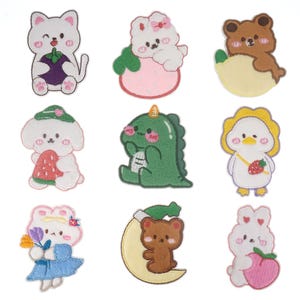 Könnte beinhalten: Neun gestickte Bügelbilder mit niedlichen Comic-Tieren und -Charakteren. Die Patches sind in verschiedenen Farben, darunter rosa, weiß, braun, gelb, grün und blau. Die Patches sind perfekt, um Kleidung, Taschen oder anderen Stoffartikeln einen Hauch von Verspieltheit zu verleihen.
