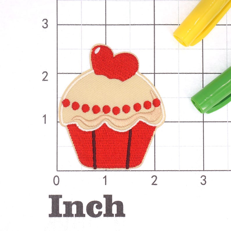 Może przedstawiać: Czerwono-biały cupcake z czerwonym sercem na g&oacute;rze. Cupcake ma około 5 cm szerokości.
