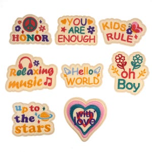 May include: Nine embroidered iron-on patches with various colorful designs and phrases, including "Honor", "You Are Enough", "Kids Rule", "Relaxing Music", "Hello World", "Oh Boy", "Up to the Stars", and "With Love".