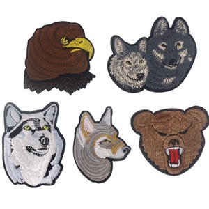 Könnte beinhalten: Satz von sechs gestickten Bügelbildern mit Tierköpfen. Die Patches beinhalten einen braunen Adler, einen grauen Wolf, einen weißen Wolf, einen grauen Wolfskopf, einen braunen Bären und einen grauen Wolfskopf.