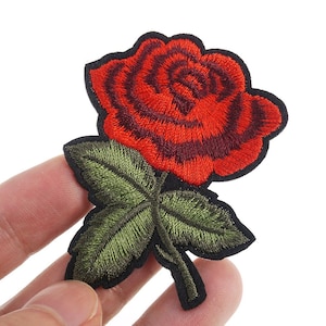Może przedstawiać: Naszywka z haftowaną czerwoną różą, zielonymi liśćmi i czarnym łodygą.