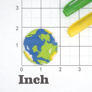 May include: A blue and green embroidered patch of the Earth on a white background. The patch is about 1 inch in diameter.
