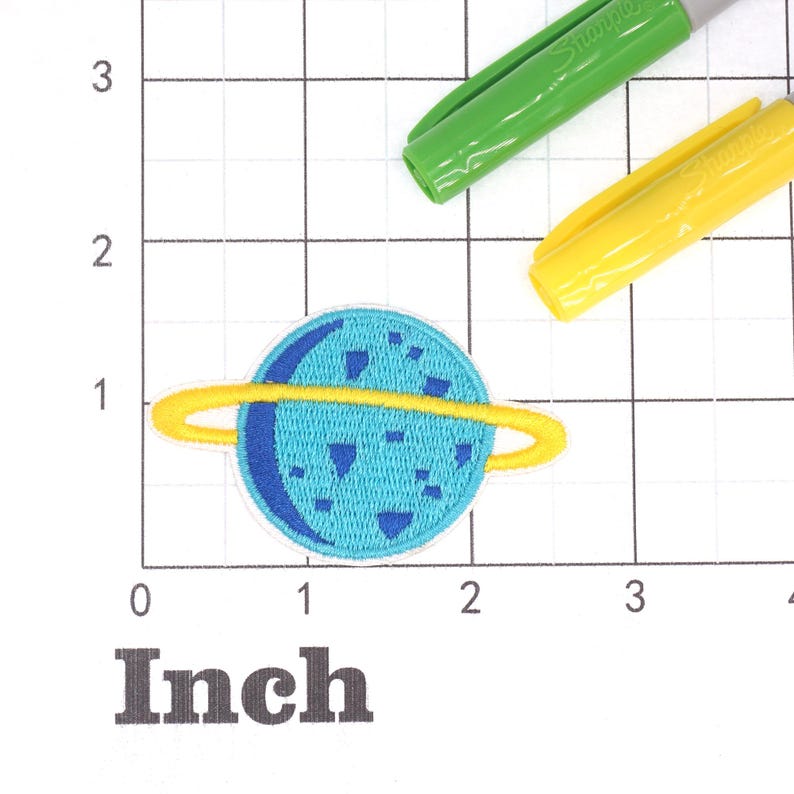 May include: A blue and yellow embroidered iron-on patch of a planet with rings. The patch is about 1 inch in diameter.