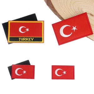 Könnte beinhalten: Rechteckige rote Aufnäher mit der türkischen Flagge, einem weißen Halbmond und Stern. Ein Aufnäher hat das Wort "TURKEY" in gelber Schrift auf einem schwarzen Streifen. Die Aufnäher befinden sich auf weißem Hintergrund.
