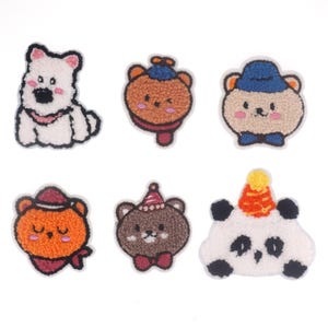 Può includere: Sei toppe ricamate da stirare con animali dei cartoni animati. Le toppe includono un cane bianco, un orso marrone con un cappello blu, un orso bianco con un cappello blu, un gatto arancione con un cappello rosso, un orso marrone con un cappello rosso e un panda bianco con un cappello rosso.