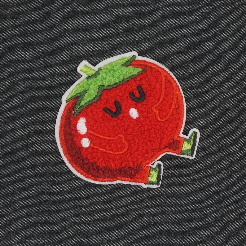 Puede incluir: Tomate de fieltro rojo con un tallo verde y una linda carita de dibujos animados. El tomate tiene dos ojos y una peque&ntilde;a boca.