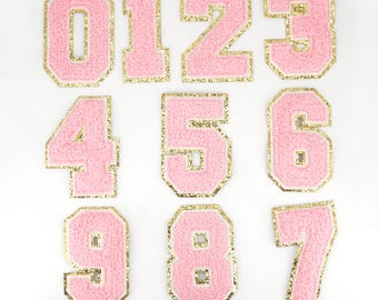 May include: Set of ten pink felt iron-on patches with gold outlines, each featuring a number from 0 to 9.