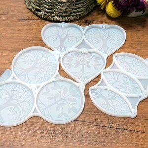 May include: A set of six white silicone molds featuring a tree of life design. The molds are shaped like hearts and circles.