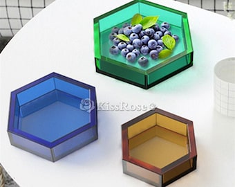 May include: Three hexagonal shaped glass dishes in different colors. The green dish has blueberries inside. The blue dish is empty. The brown dish is empty.
