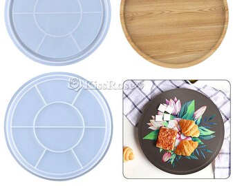 May include: Two light blue silicone trays with seven circular compartments each. The trays are for making resin crafts. A wooden tray with a natural wood grain finish is also shown. A dark gray plate with a floral design and two croissants is shown.
