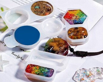 May include: A set of clear silicone molds for making resin jewelry. The molds are shaped like a circle, a hexagon, a rectangle, and a teardrop. The molds are filled with colorful resin and glitter.