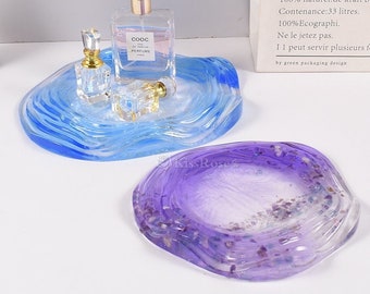 May include: Two resin trays, one blue and one purple, with a wavy design. The blue tray has three glass perfume bottles on it. The purple tray has a subtle sparkle.