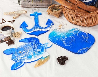 May include: Three resin serving trays with ocean wave designs. The trays are shaped like an anchor, a turtle, and a rectangle. The trays are blue and white with white swirls resembling waves.