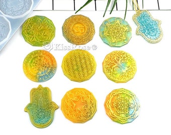 May include: A collection of resin pendants and molds in various shapes, including a Hamsa hand, circular designs with geometric patterns, and a pendant with a gold chain. The pendants feature yellow, green, and blue hues.