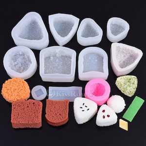 Pode incluir: Um conjunto de 12 moldes de silicone transparentes para fazer alimentos em miniatura, incluindo triângulos, quadrados e círculos. Os moldes são mostrados com vários alimentos acabados, incluindo bolinhos de arroz, pão e uma bola rosa.
