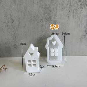 May include: Two white silicone molds shaped like houses with a heart and windows. The larger mold is 9.5 cm tall and 5.7 cm wide. The smaller mold is 8 cm tall, 4.2 cm wide, and 2 cm deep. The molds weigh 28.8 grams.