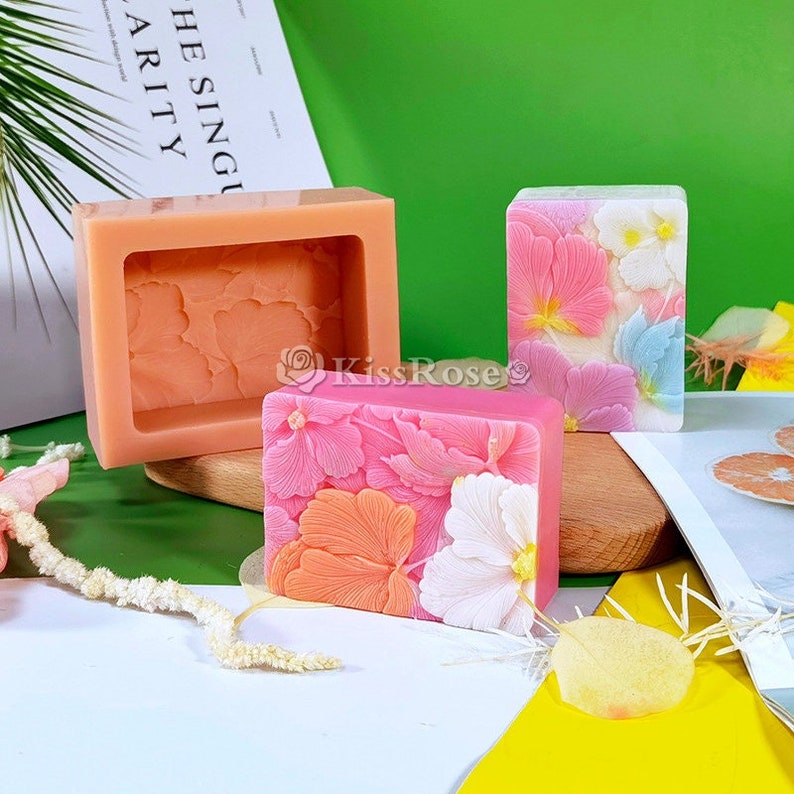 May include: Three pink and white floral soap bars, two in silicone molds and one ready to use. The soap bars have a detailed floral design.