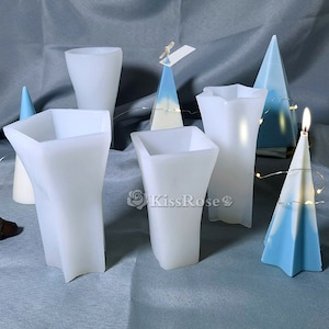 Pode incluir: Cinco moldes de vela de silicone branco em diferentes formas: uma estrela, um quadrado, um cone e duas variações diferentes de uma forma de vaso. Os moldes estão sobre uma superfície cinza.