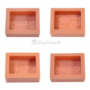 May include: Four silicone molds for making soap. Each mold is rectangular and has a different design: flowers, leaves, a daisy, and a swirling pattern. The molds are a light peach color.