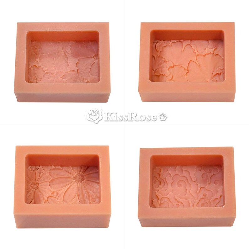 May include: Four silicone molds for making soap. Each mold is rectangular and has a different design: flowers, leaves, a daisy, and a swirling pattern. The molds are a light peach color.
