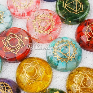 May include: Seven round, polished stones with gold geometric designs. Each stone is a different color, including red, green, blue, white, and yellow.