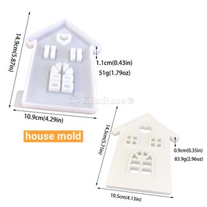 May include: Two white silicone house-shaped molds. The mold on the left is 5.87 inches tall and 4.29 inches wide. The mold on the right is 5.71 inches tall and 4.13 inches wide. Both molds have a heart-shaped cutout at the top and windows and a door cutout.