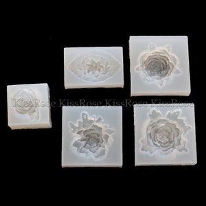 May include: Five silicone molds for making various flower shapes. The molds are white and have a smooth surface. The flower shapes include a single rose, a rose with leaves, and three different peony shapes.