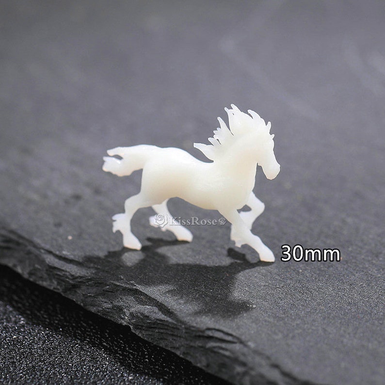 Op de afbeelding: Witte resin paardenbeeldje, 30 mm groot. Het paard rent met zijn manen in de wind.