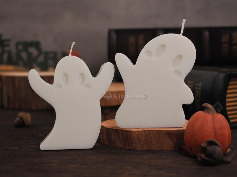 Op de afbeelding: Twee witte geestenvormige kaarsen op houten bases. De kaarsen zijn gemaakt van was en hebben een eenvoudig ontwerp.