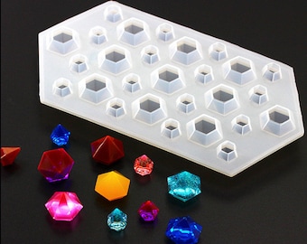 Puede incluir: Un molde de silicona blanco con 24 cavidades en forma de diamante. El molde se utiliza para crear joyas de resina. Hay varios diamantes de resina de colores junto al molde.