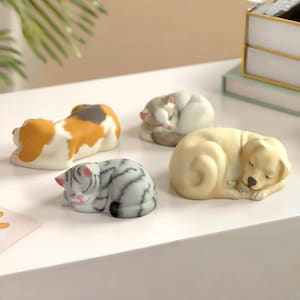 May include: Four sleeping animal ornaments: a beagle, two cats, and a golden retriever. The beagle is white, brown, and tan. One cat is gray and white striped, and the other is white and gray. The golden retriever is light yellow.